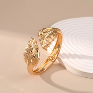 Detailed view of golden leaf cuff bracelet with fine texture on white display stand