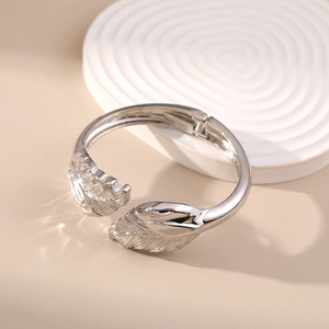 Detail of silver feather cuff bracelet showing polished texture and hinge on stone tray