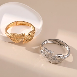 Detail of gold and silver feather-shaped bracelets with intricate metal textures