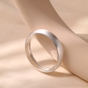 Detail view of silver metal bangle with brushed matte finish and smooth inner surface