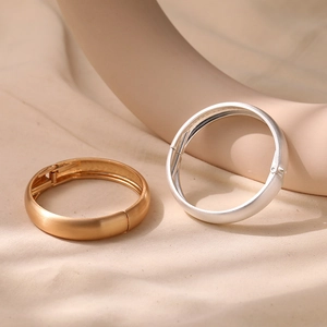 Detail of matte gold and silver bangles with brushed metal texture and side hinge