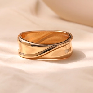 Close-up of wavy gold-plated bangle with a polished finish and spring-hinge clasp