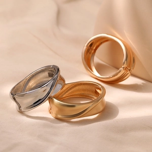 Detail of twisted metal bangle set in polished gold, silver, and brushed matte gold finishes