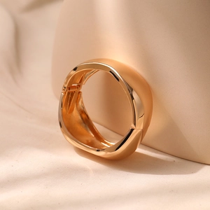 Detail of a wide gold cuff bracelet featuring organic shapes and a sleek hinge mechanism