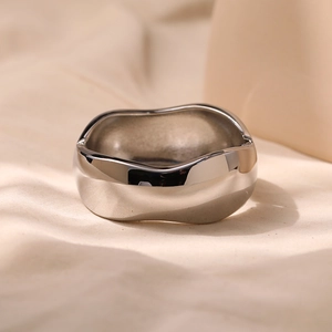 Detailed close-up of a silver irregular wavy metal ring with a polished mirror finish
