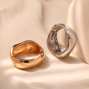 Detailed close-up of organic wavy gold and silver bangles with hinge closure design