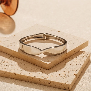 Detailed view of polished silver hinge bangle on minimalist stone display stand