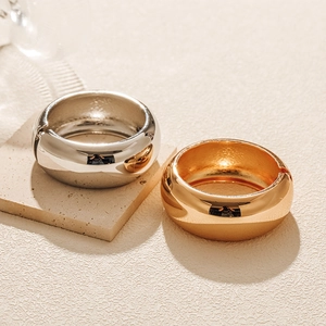 Polished gold and silver minimalist open bangles displayed on stone surface textures
