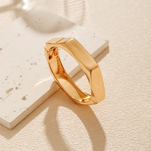 Detailed view of golden geometric bangle with polished finish on marble surface