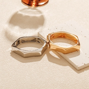 Close-up of minimalist gold and silver hexagonal bangles on a marble background