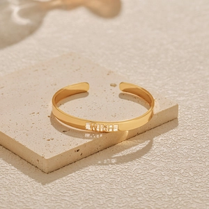 Detailansicht des goldenen Armreifs mit WISH-Schriftzug auf einem strukturierten Stein
