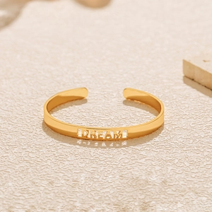 Nahaufnahme eines vergoldeten Armreifs mit filigranem DREAM-Schriftzug-Detail