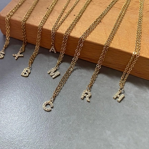 Dettaglio dei ciondoli con iniziali placcati in oro 14K e zirconi su catena fine