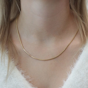 Elegante vergoldete Edelstahl-Schlangenkette getragen von einem weiblichen Model