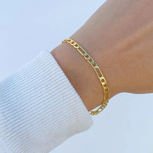 Klassisches goldenes Figaro-Kettenarmband für Damen und Herren am Handgelenk eines Models