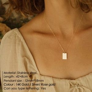Detailopname van een dubbele goudkleurige ketting met vierkante hanger bij een model