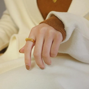 Gros plan d'une bague rectangulaire minimaliste en acier inoxydable doré au doigt