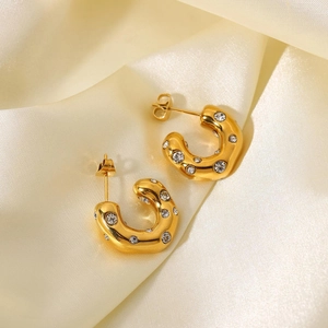 Macro detail of 18K gold plated C-shape hoop earrings with hammered texture and zircons