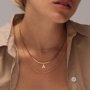 Close-up of gold layered snake chain necklace with sparkling zircon letter A pendant