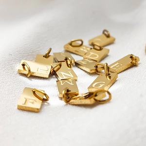 Detailed macro view of gold-plated rectangular alphabet pendants for DIY jewelry design