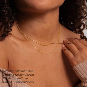 Detail of layered stainless steel snake and water wave chains in golden finish