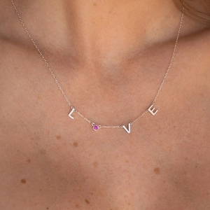 Collar LOVE de acero inoxidable pulido con una piedra rosa lucido por una modelo