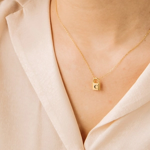 Minimalist gold snake chain necklace with a letter C lock pendant on a female neck