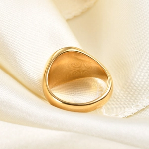 Macro shot of minimalist polished gold ring on white satin fabric showing metal texture