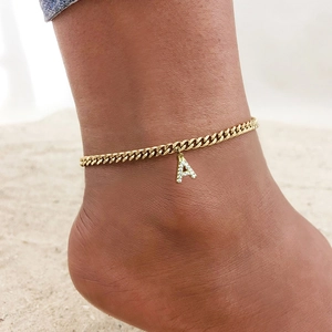Bracelet de cheville gourmette dorée avec pendentif lettre A strass porté à la plage