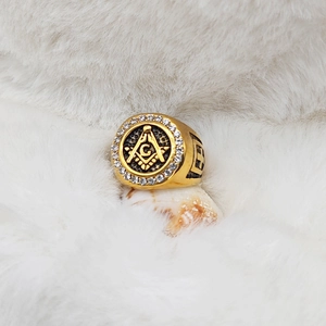 Detailed macro of gold Masonic G-symbol ring with white rhinestones on shell display