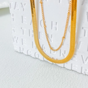 Detail of gold-plated double-layered necklace featuring flat herringbone and bead chains