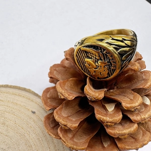 Macro detail of Caesar gold relief signet ring with lion engraving on pine cone