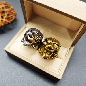 Detailed close-up of tiger head rings in gold and silver finish inside a jewelry box