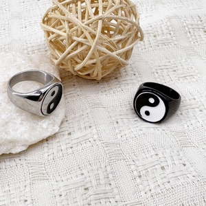 Close-up of Tai Chi Yin Yang rings in silver and black on a white textured background