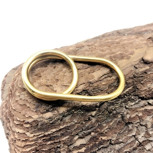 Macro detail of matte gold double-ring nested design on a rustic wood texture background