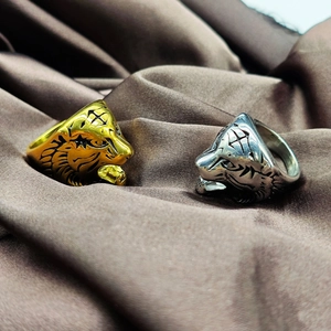 Detailed view of fierce gold and silver tiger rings on brown silk fabric background