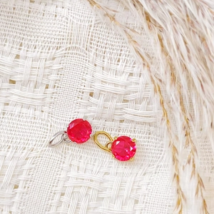Macro detail of round 7x7mm ruby red zircon pendants with gold and silver bail charms