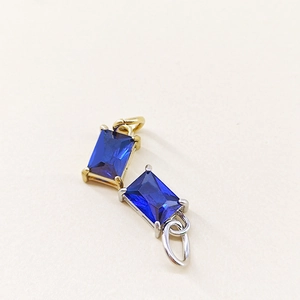 Detail of rectangular blue zircon birthstone charms with polished gold and silver plating