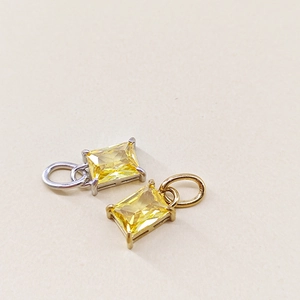 Detail of emerald-cut yellow zircon pendants in gold and silver plated settings