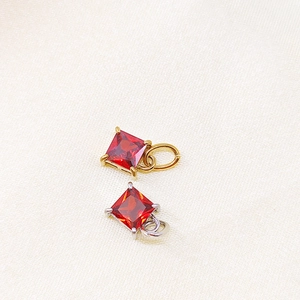 Detail of square red zircon pendant with four-claw setting in gold and silver finish