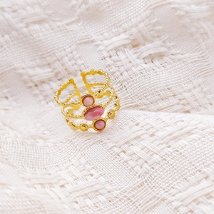 Detalle del anillo de tres capas chapado en oro de 18K con tres piedras rosas sobre tela