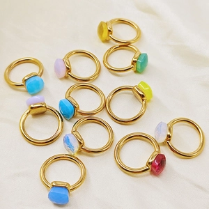 Macro shot of colorful cushion-cut gemstone rings scattered on white silk fabric