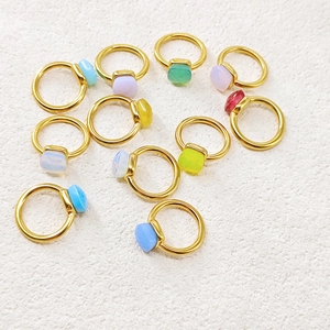 Flat lay of colorful cushion-cut gemstone rings on a textured white surface
