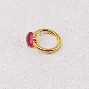 Detailed macro view of gold geometric ring featuring a faceted dark pink zircon stone
