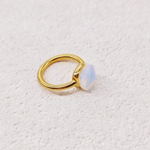 Detailed close-up of a gold ring featuring a soft milky white cushion-cut gemstone inlay