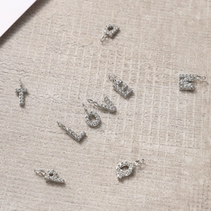 Macro shot of silver metal letter charms L, O, V, E with clear zircon inlays for DIY jewelry