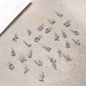 Macro view of 26 silver alphabet charms with cubic zirconia and round hanging rings