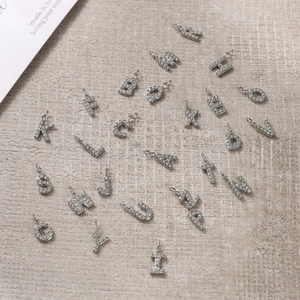 Macro detail of 26 diamond-set silver alphabet charms for DIY jewelry making