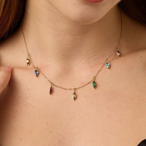 Elegante collana dorata con sette gemme colorate dal taglio marquise indossata al collo