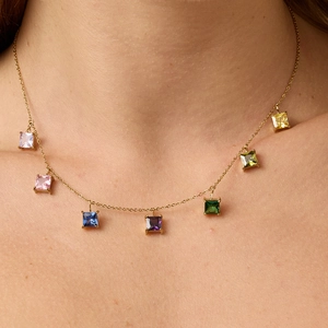 Dettaglio di una collana a catena dorata con sette pendenti in zircone quadrati colorati